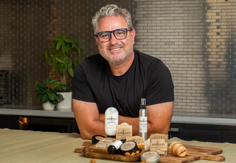 Apricoty founder Kevork Douzadjian sitting with handcrafted skincare products.